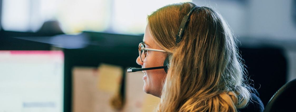 En kundservicemedarbetare pratar med en kund via sitt headset.