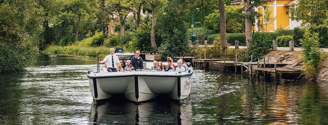 En skärgårdsbåt färdas över vattnet i en lummig miljö.