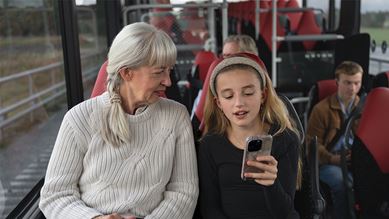 Äldre kvinna och barn tittar på mobil ombord på bussen