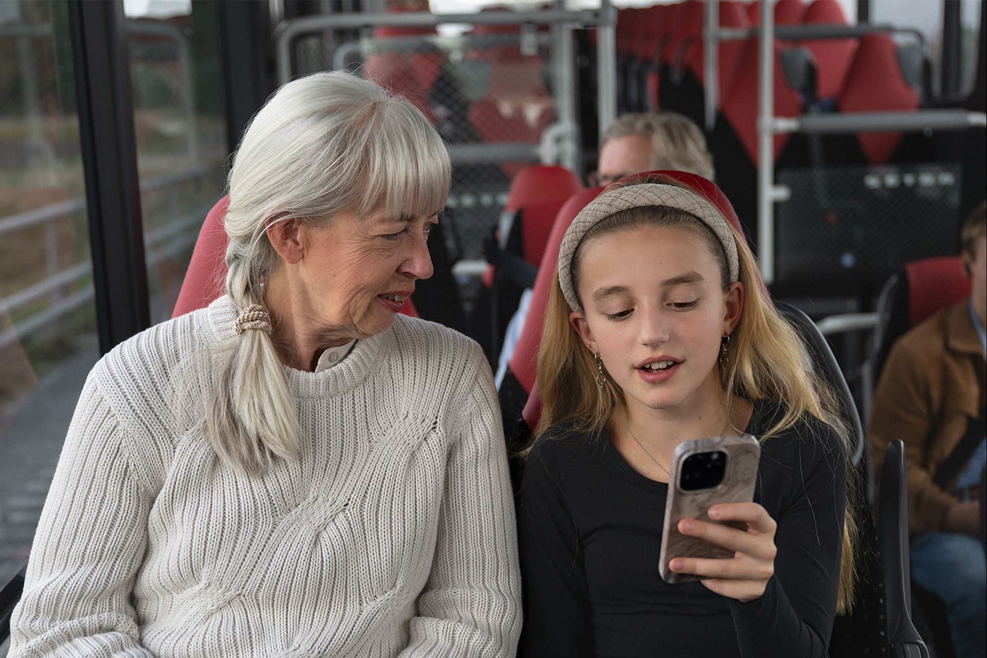 Äldre kvinna och barn tittar på mobil ombord på bussen