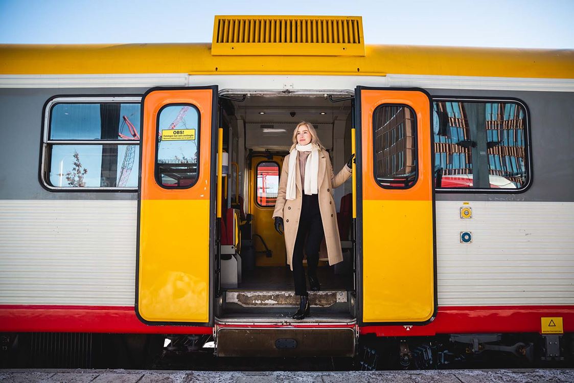 En tjej i vinterkläder står ombord på ett Krösatåg.