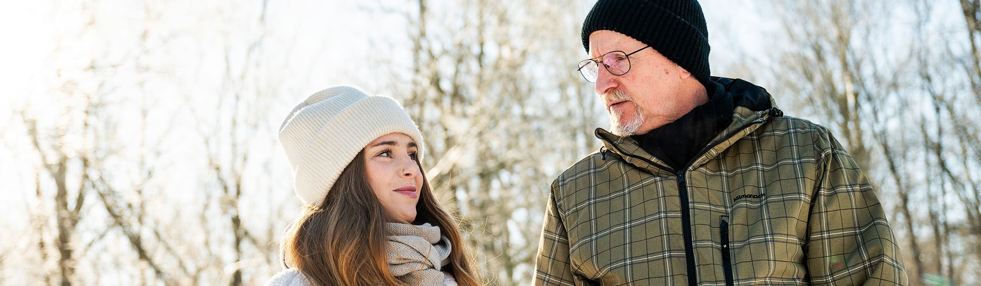 En man och en kvinna tittar ner i telefon i väntan på bussen.