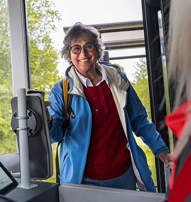 Kvinna kliver ombord på en buss och betalar med sin telefon.