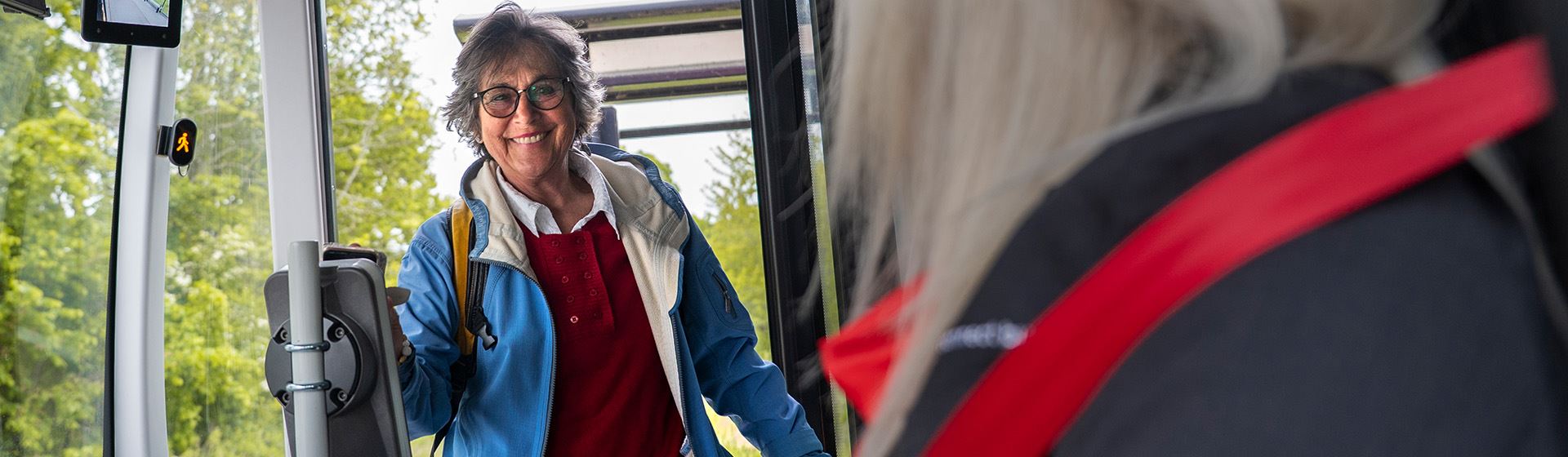 Kvinna kliver ombord på en buss och betalar med sin telefon.