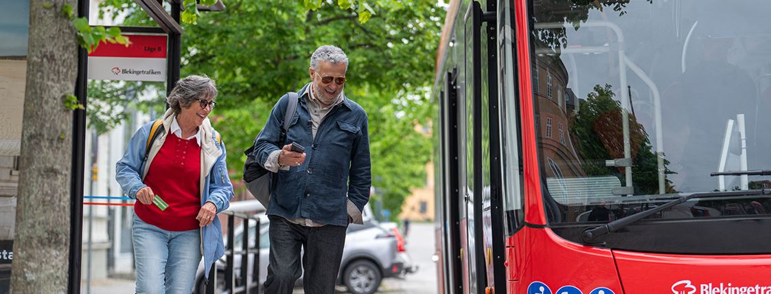 Flera resenärer går från en busshållplats och framför bussen.