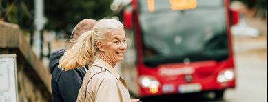 Glad kvinna väntar på bussen.