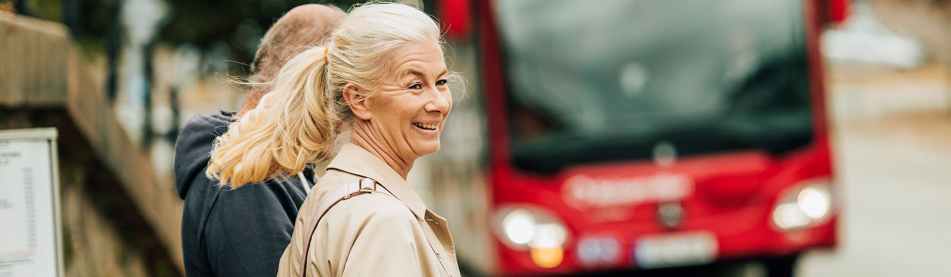 Glad kvinna väntar på bussen.