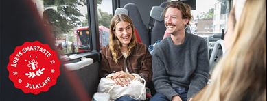 Två personer åker buss, på bilden syns ett sigill med texten "Årets smartaste julklapp"