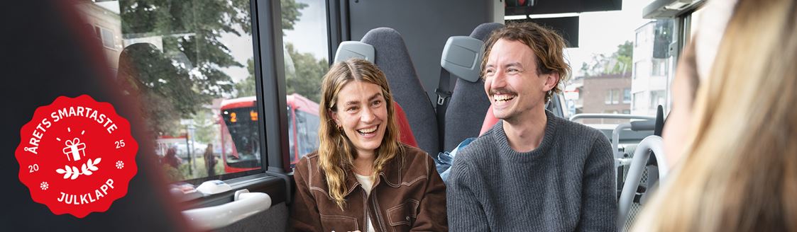 Två personer åker buss, på bilden syns ett sigill med texten "Årets smartaste julklapp"