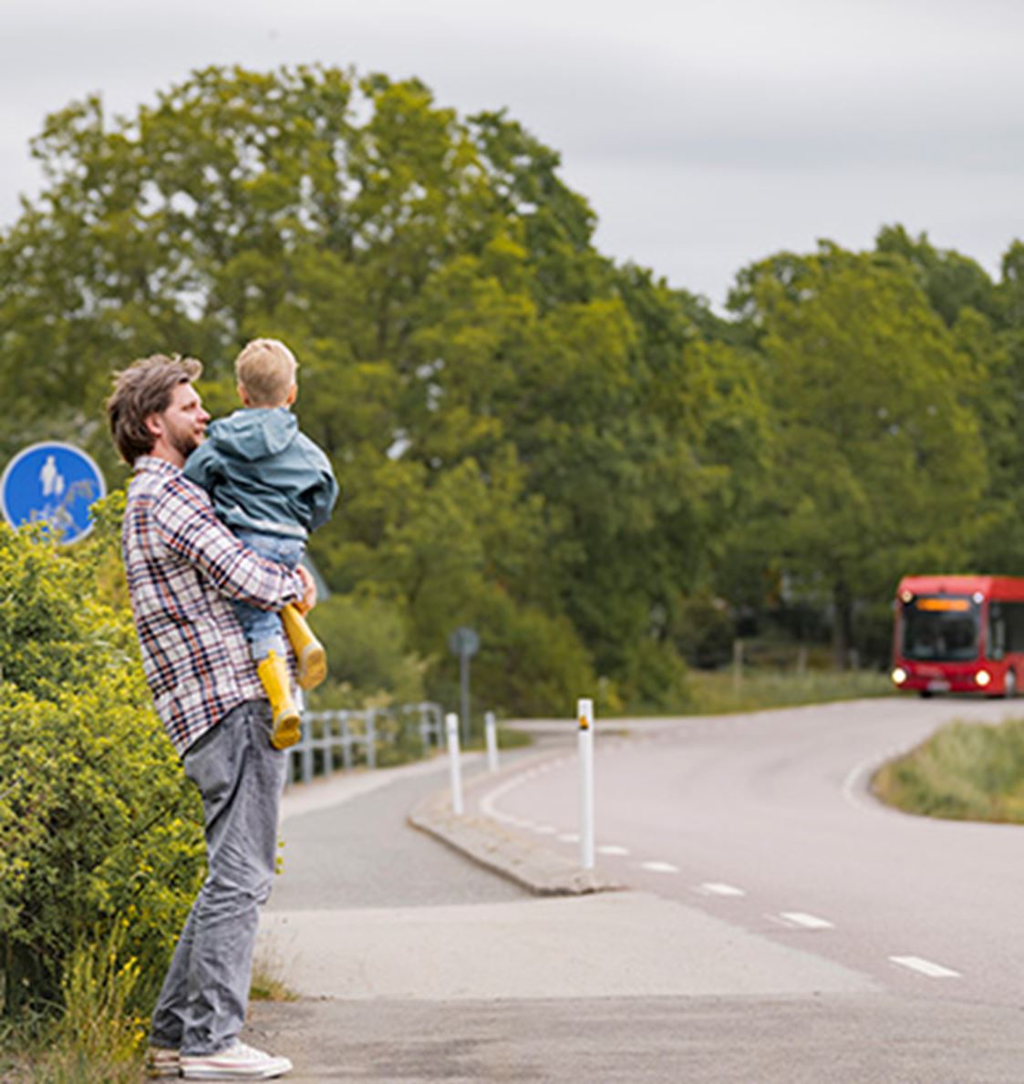 en man och ett barn väntar på bussen.