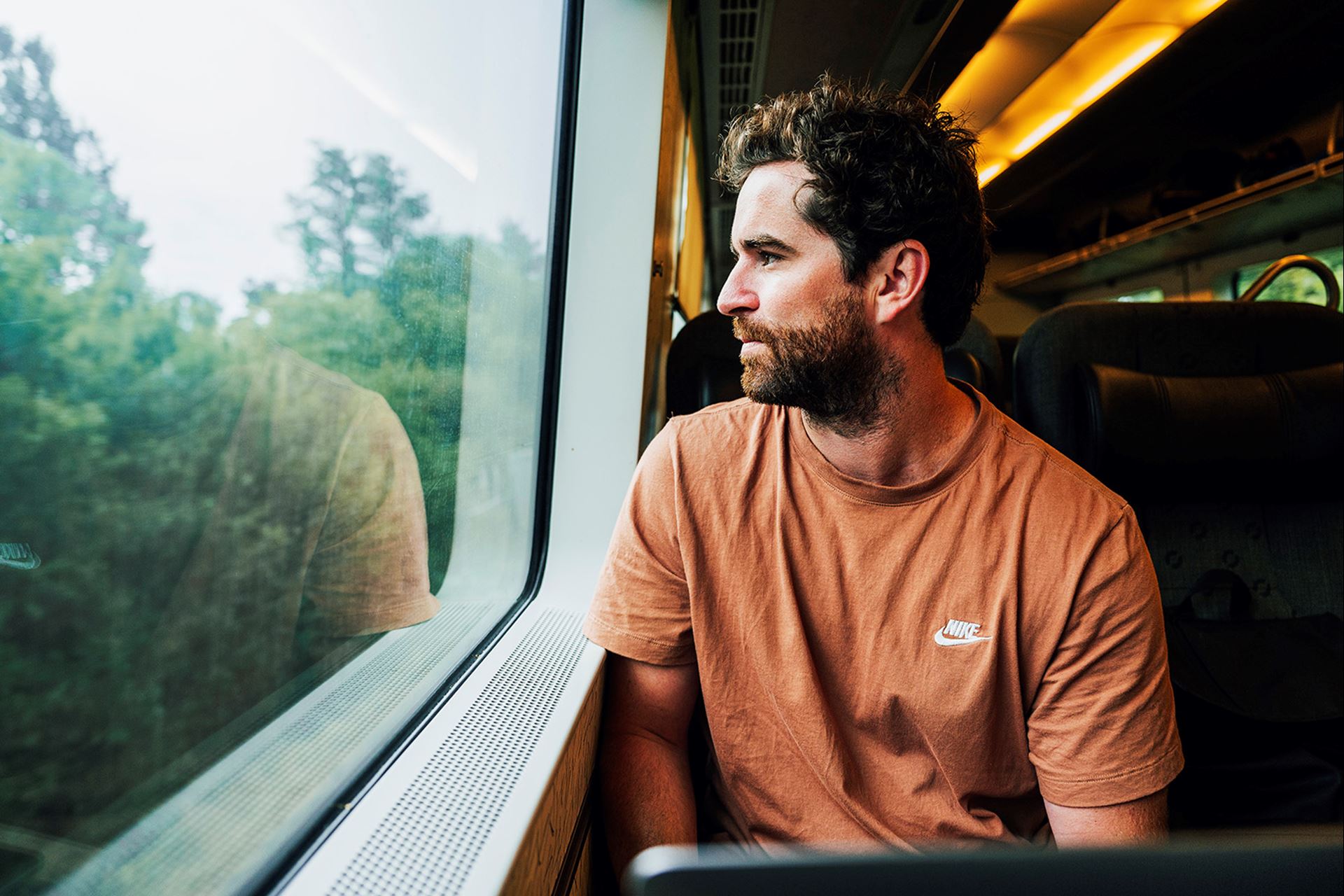 En kille sitter ombord ett tåg och tittar ut genom fönstret.
