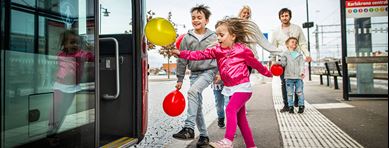 Barn med ballonger springer ombord på buss
