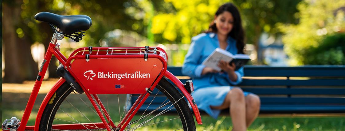 Kvinna står vid en röd cykel.