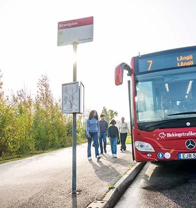 Fyra ungdomar står vid en hållplats och är på väg att gå ombord på bussen.