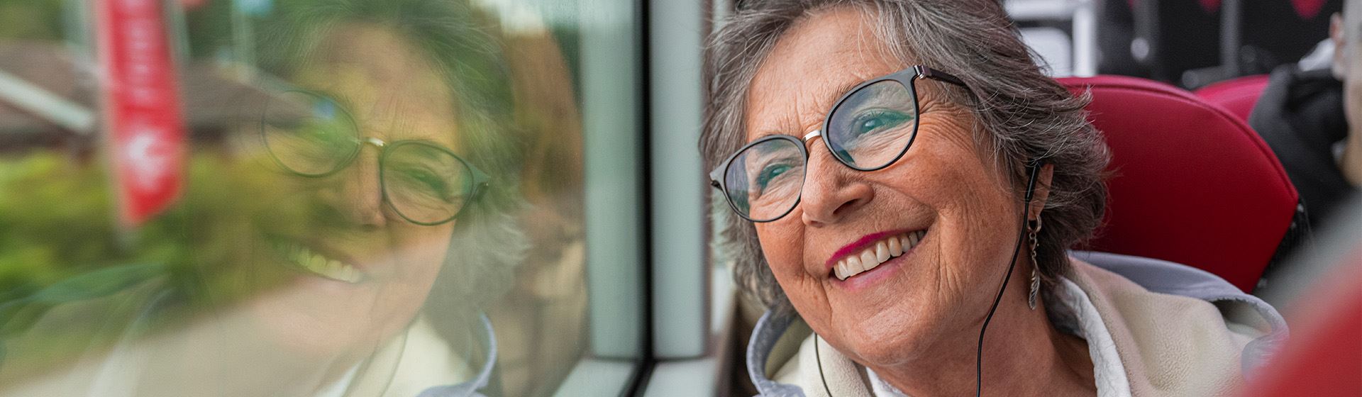 Senior kvinna tittar ut genom ett bussfönster.