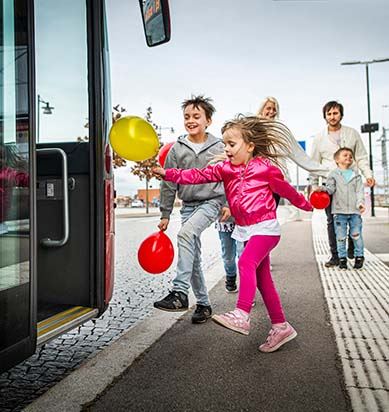 Två barn hoppar skrattandes ombord på en buss.