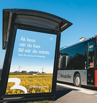 En buss passerar en hållplats med en affisch:  "Åk buss när du kan. Bil när du måste."