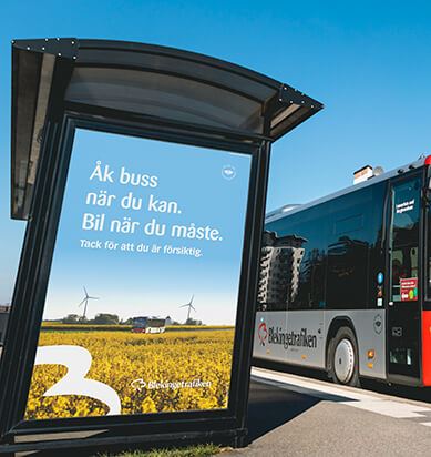 En buss passerar en hållplats med en affisch: "Åk buss när du kan. Bil när du måste."