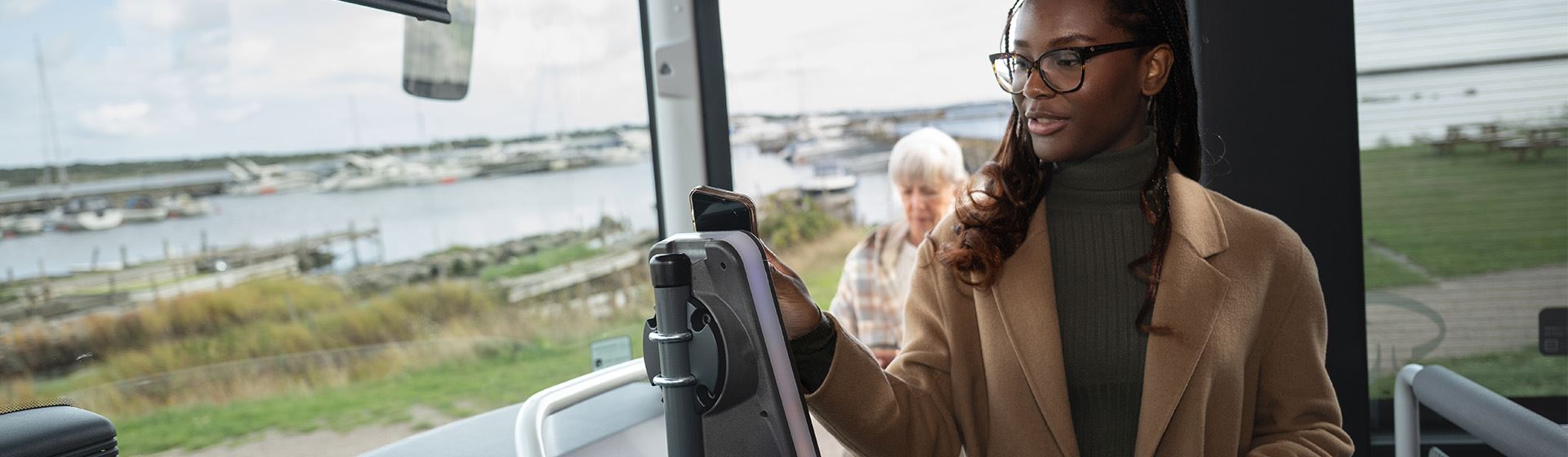 En resenär håller en smartphone mot en biljettläsare på bussen.