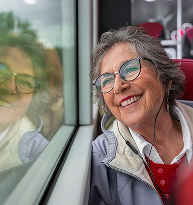 En leende kvinna sitter och tittar ut genom fönstret ombord på en buss.
