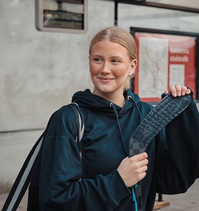 En person håller i ett grönt resekort. I bakgrunden syns snö.