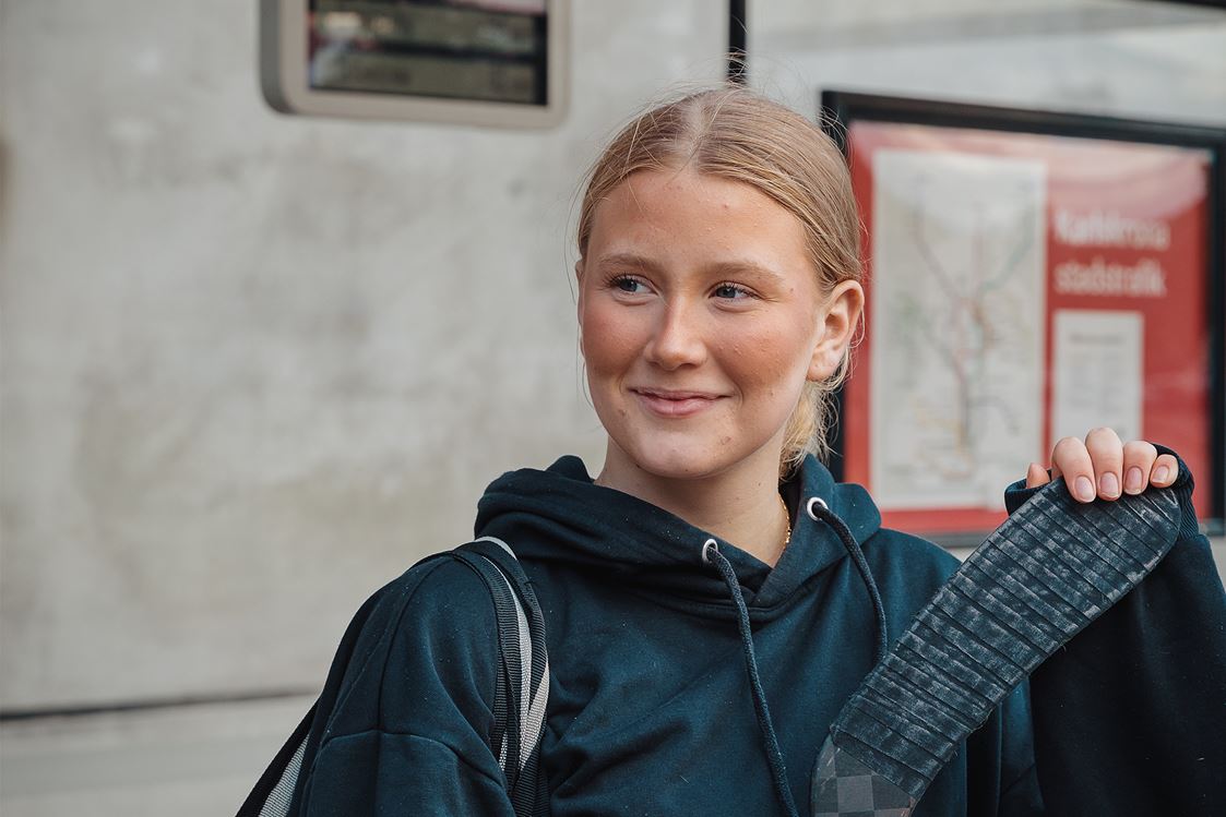 En person håller i ett grönt resekort. I bakgrunden syns snö.