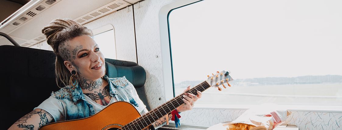 En kvinna sitter med en gitarr ombord på Öresundståget.