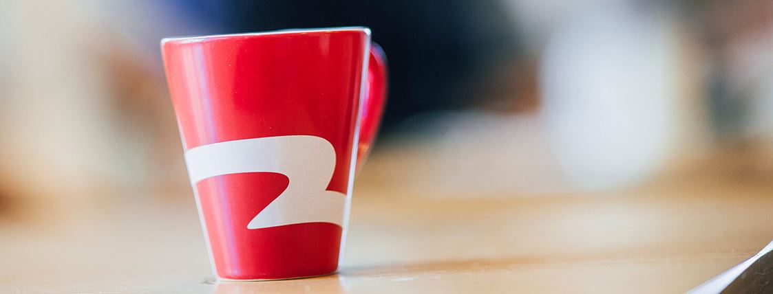 En röd kaffekopp med Blekingetrafikens logotyp på.