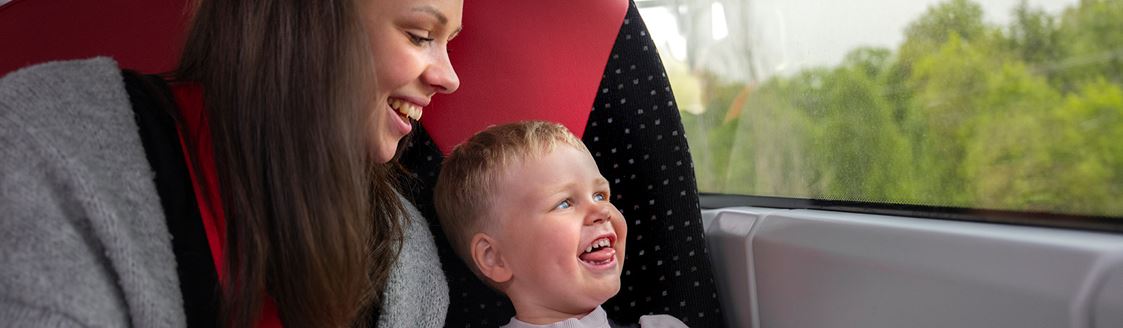 Förälder och barn tittar ut genom fönstret på bussen.