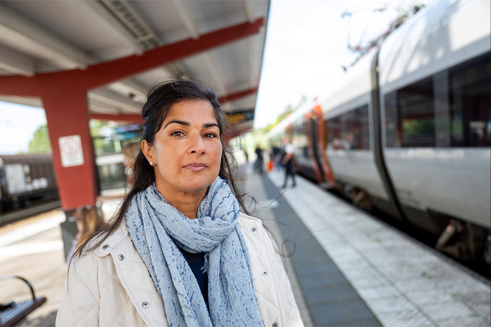 En kvinna står vid tåget och tittar mot kameran