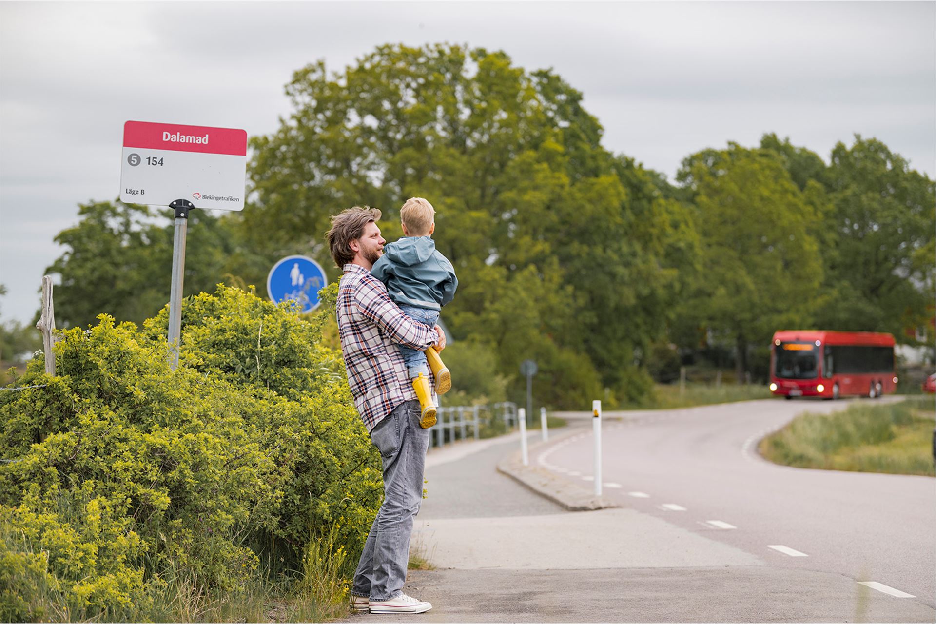En pappa och ett barn väntar på bussen.