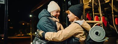 Två personer i mörker möts framför en buss.