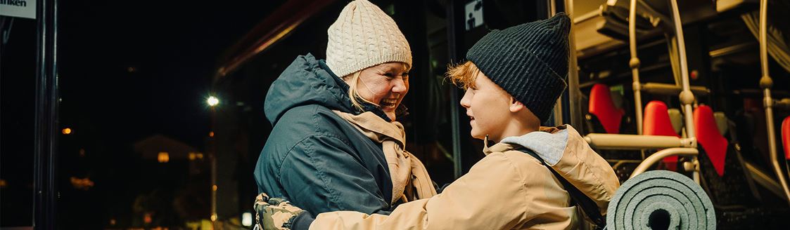 Två personer i mörker möts framför en buss.
