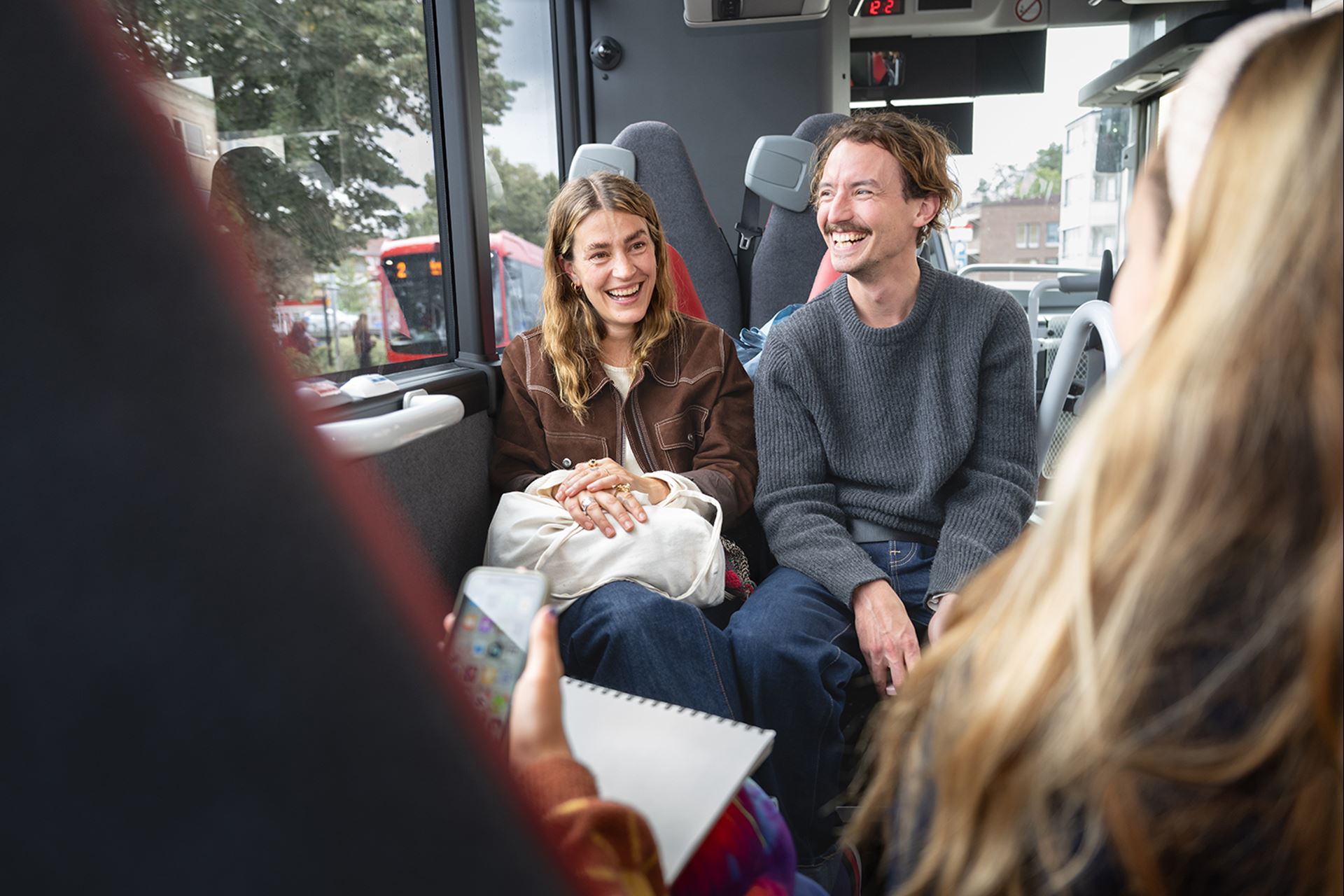 Två resenärer sitter på en buss och skrattar.